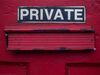 A sign which reads 'private' above a red letterbox on a red door