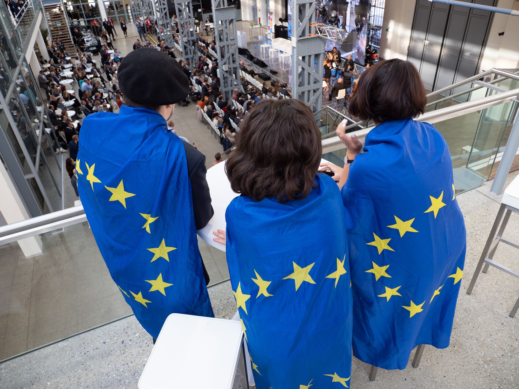Three people at the 2018 Fundamental Rights Forum, wearing EU Flags