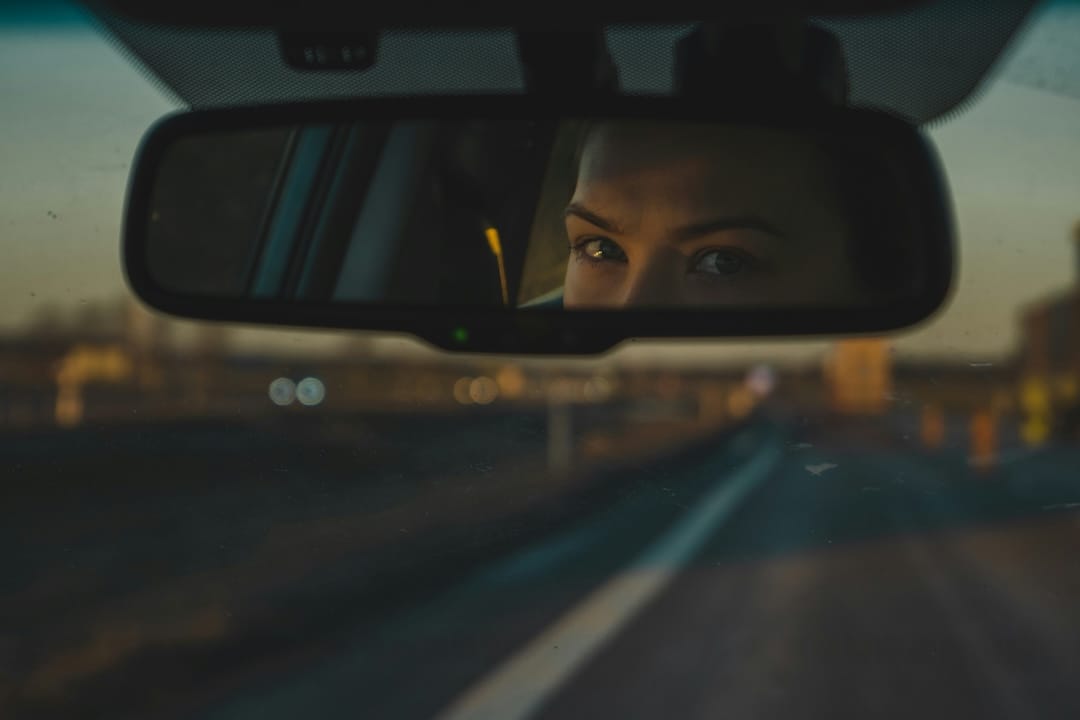 A woman driver looking in the rearview mirror of her car