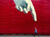 A finger painted on a wall pointing down at a man walking along
