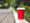 A red disposable coffee cup discarded by a road